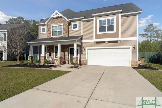 craftsman-style house with a front yard, concrete driveway, covered porch, and stone siding