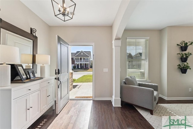 foyer entrance with baseboards, plenty of natural light, arched walkways, and dark wood finished floors