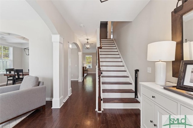 stairway featuring a wealth of natural light, baseboards, arched walkways, and hardwood / wood-style flooring