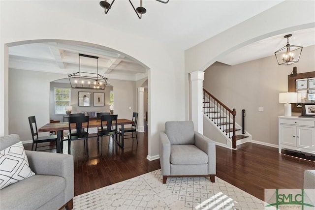 living area featuring coffered ceiling, stairs, baseboards, and wood finished floors