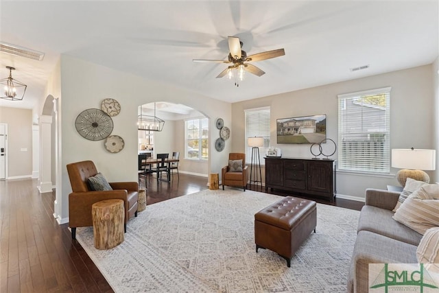 living area featuring visible vents, arched walkways, and dark wood-style flooring