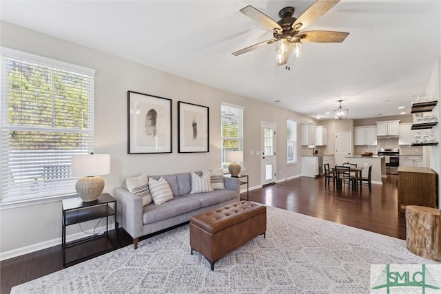 living area with dark wood-style floors, baseboards, and ceiling fan