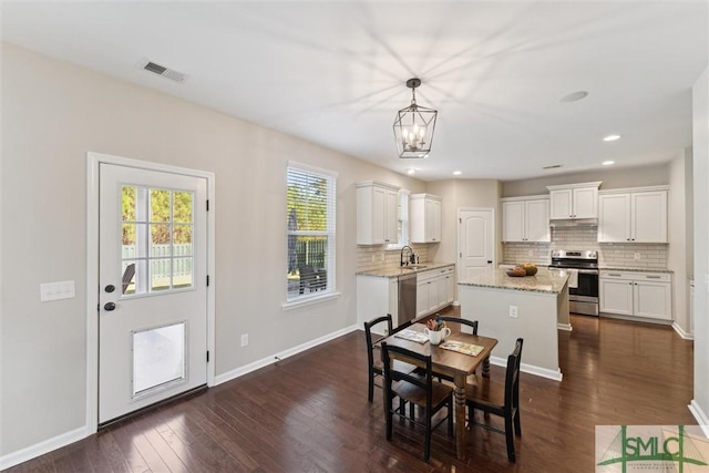 dining area with dark wood-style floors, visible vents, baseboards, recessed lighting, and a notable chandelier