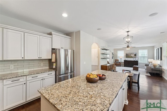 kitchen with tasteful backsplash, a center island, freestanding refrigerator, white cabinets, and dark wood-style flooring