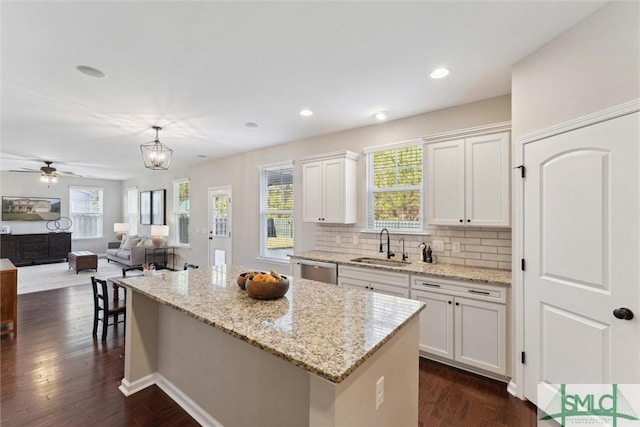 kitchen featuring a kitchen island, a sink, dark wood-type flooring, white cabinets, and dishwasher