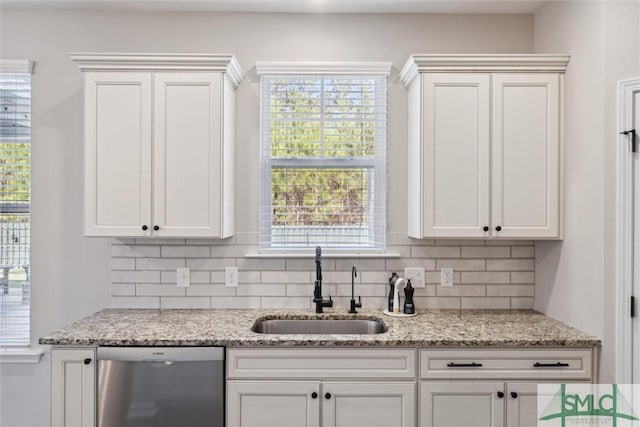 kitchen featuring tasteful backsplash, white cabinets, dishwasher, and a sink