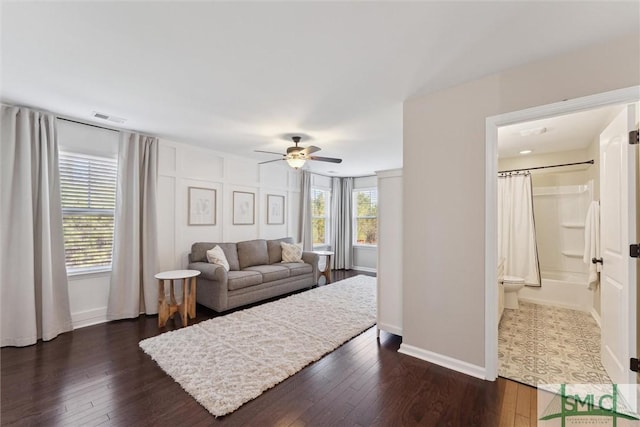 living area with a ceiling fan, dark wood-style floors, visible vents, and baseboards