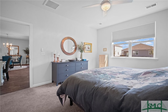 carpeted bedroom with visible vents, ceiling fan with notable chandelier, and baseboards