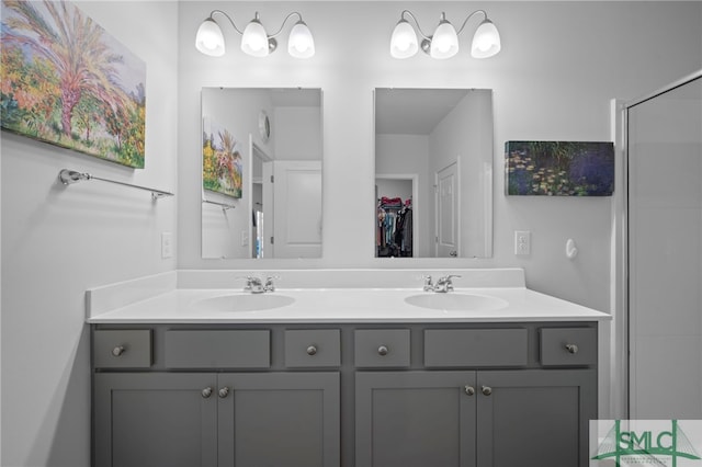 bathroom with a sink, a shower with shower door, and double vanity