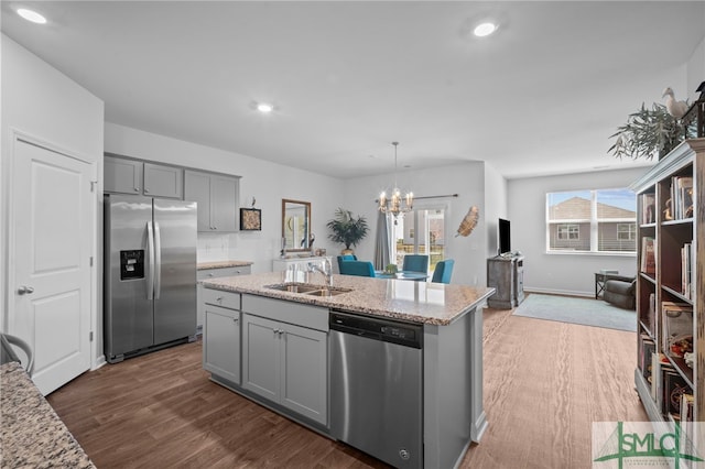 kitchen featuring light stone counters, gray cabinets, a sink, dark wood-type flooring, and appliances with stainless steel finishes