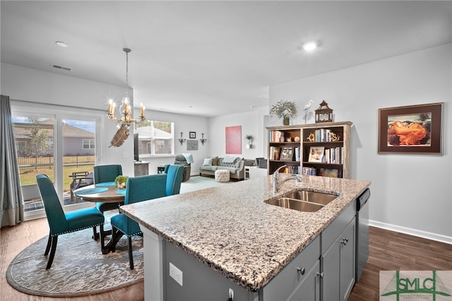 kitchen featuring visible vents, dark wood finished floors, gray cabinetry, a sink, and stainless steel dishwasher