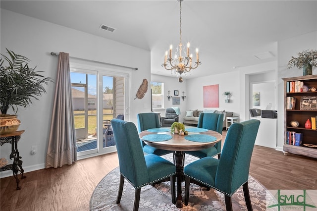 dining space with visible vents, baseboards, an inviting chandelier, and wood finished floors