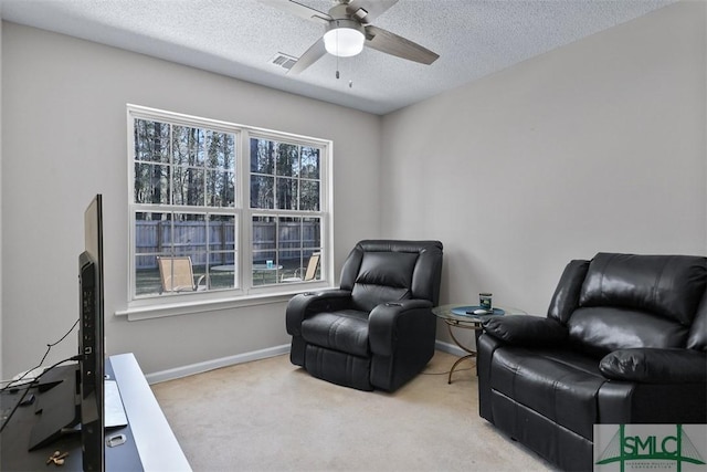 sitting room with visible vents, carpet floors, plenty of natural light, and a ceiling fan