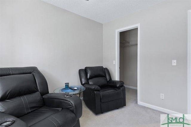 living area featuring light carpet, a textured ceiling, and baseboards