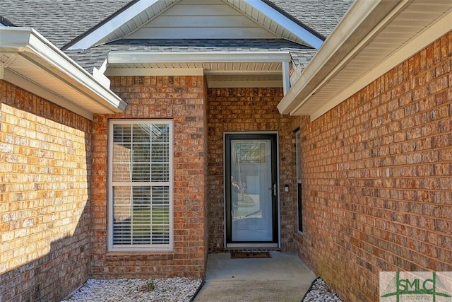 property entrance featuring brick siding and a shingled roof