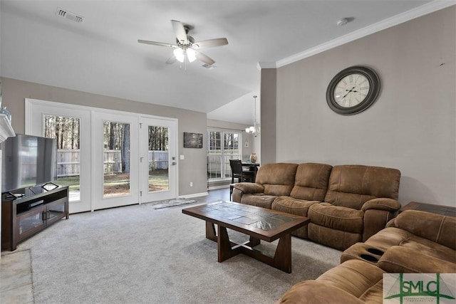 living area with visible vents, carpet floors, lofted ceiling, crown molding, and ceiling fan with notable chandelier