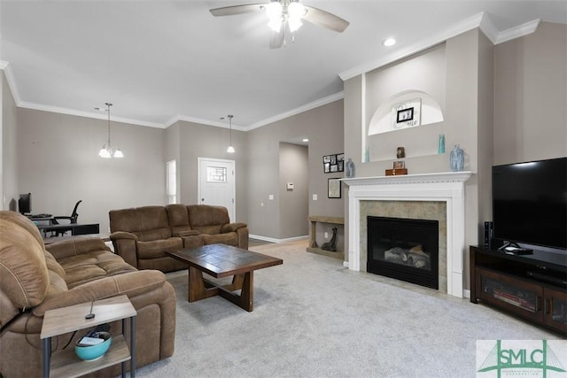 carpeted living area featuring baseboards, ceiling fan with notable chandelier, crown molding, and a tiled fireplace