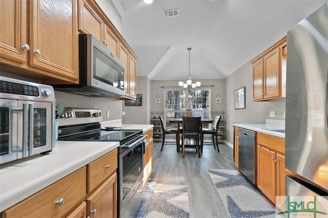 kitchen featuring visible vents, light countertops, vaulted ceiling, light wood-style floors, and stainless steel appliances