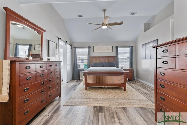 bedroom featuring a barn door, multiple windows, visible vents, and vaulted ceiling