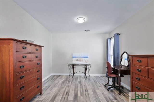 home office with light wood finished floors, visible vents, and baseboards