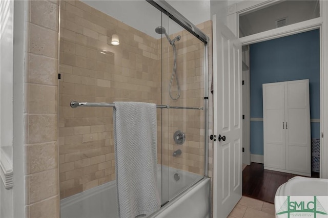 full bathroom with tile patterned flooring, visible vents, and shower / bath combination with glass door