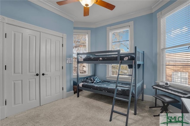 bedroom with ornamental molding, a closet, carpet flooring, baseboards, and ceiling fan