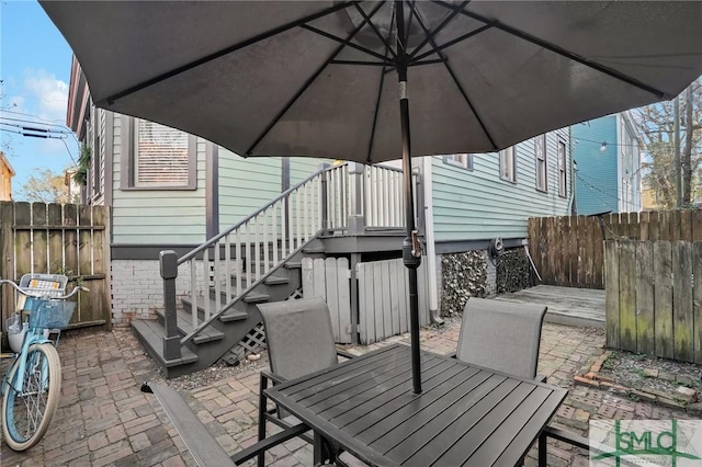 view of patio featuring stairs, outdoor dining area, and fence