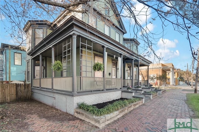 view of property exterior with a porch and fence