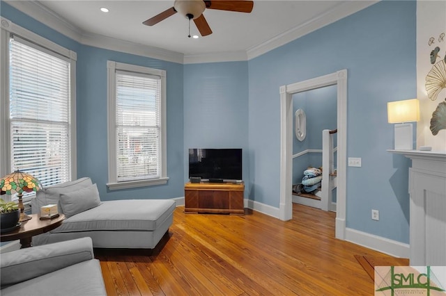 living room featuring baseboards, wood finished floors, ornamental molding, and a ceiling fan