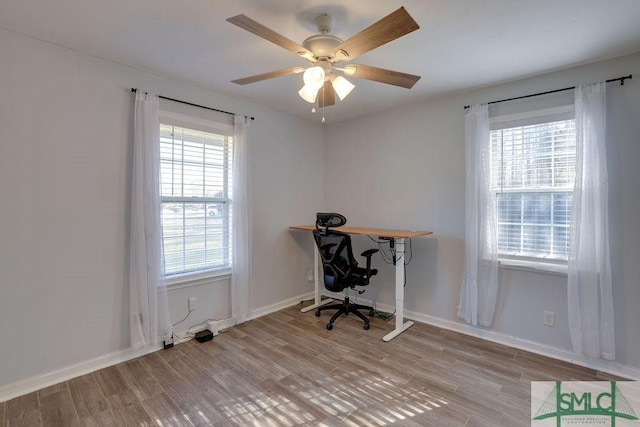 office space featuring a ceiling fan, light wood-style floors, and baseboards