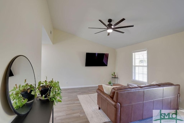 living area featuring baseboards, light wood-style flooring, a ceiling fan, and vaulted ceiling