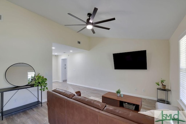 living room with baseboards, light wood finished floors, a ceiling fan, and vaulted ceiling