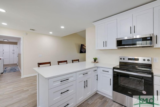 kitchen featuring visible vents, a peninsula, stainless steel appliances, light countertops, and light wood-type flooring