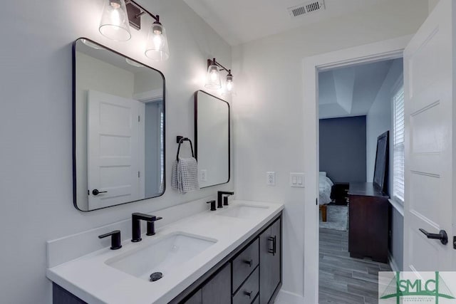 ensuite bathroom with double vanity, visible vents, connected bathroom, and a sink