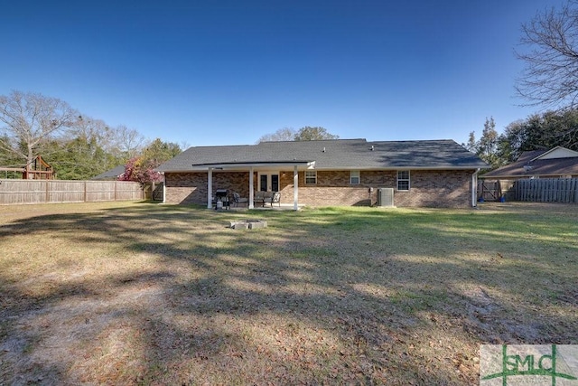 back of property with a fenced backyard, a lawn, a patio, and central AC