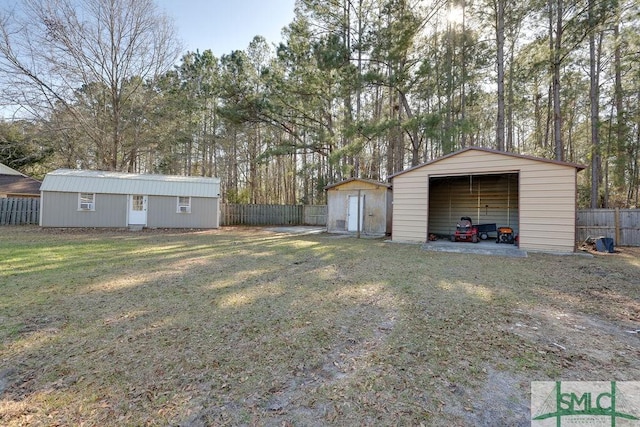 view of yard with an outbuilding, fence, a garage, and driveway