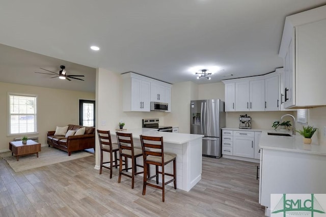 kitchen with open floor plan, stainless steel appliances, light countertops, and a sink