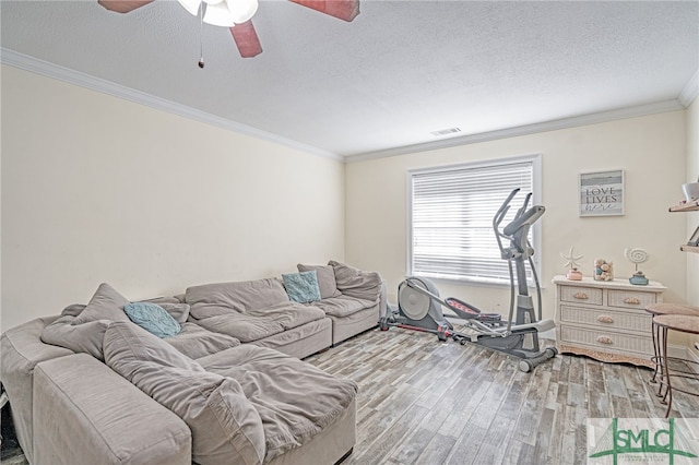 living area featuring visible vents, ornamental molding, wood finished floors, a textured ceiling, and a ceiling fan