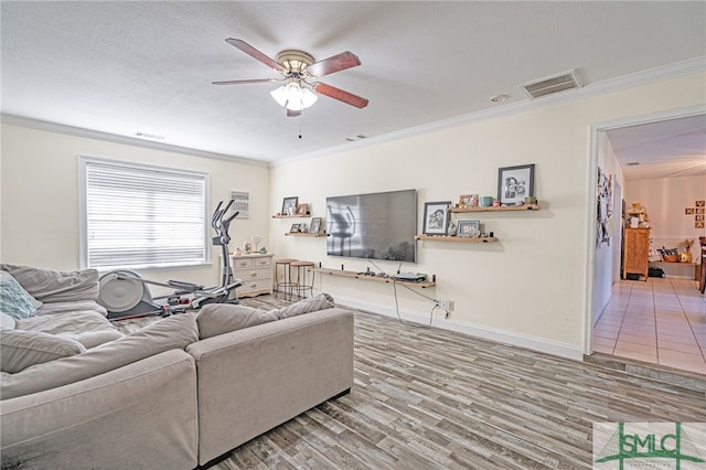 living room with visible vents, ceiling fan, ornamental molding, wood finished floors, and a textured ceiling