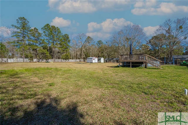 view of yard with a wooden deck, a storage shed, an outdoor structure, and fence