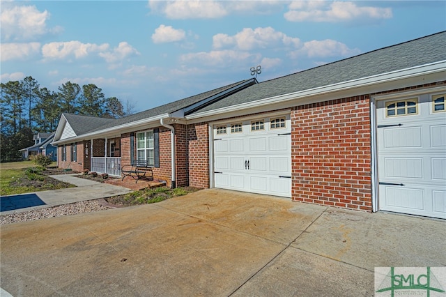 view of front of house with a porch, a garage, brick siding, and driveway