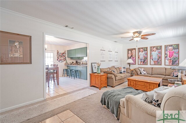 living area featuring light tile patterned floors, visible vents, light colored carpet, and crown molding