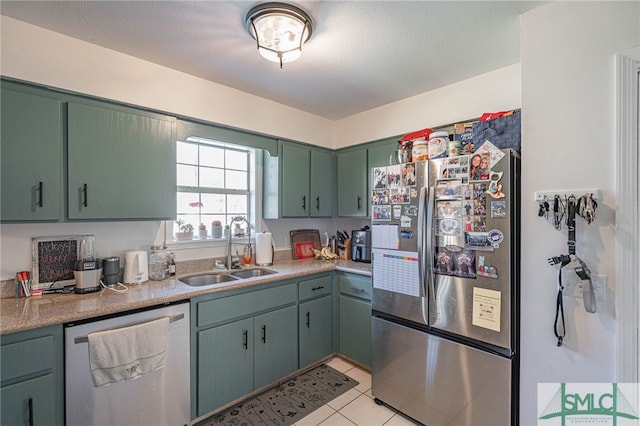 kitchen with a sink, appliances with stainless steel finishes, light tile patterned flooring, light countertops, and green cabinetry