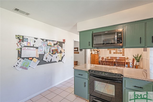 kitchen with stainless steel microwave, visible vents, green cabinets, light countertops, and black / electric stove