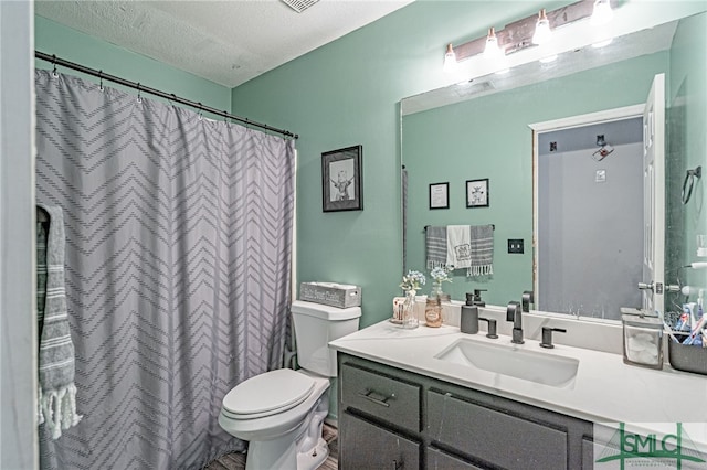 full bathroom featuring curtained shower, toilet, vanity, and a textured ceiling