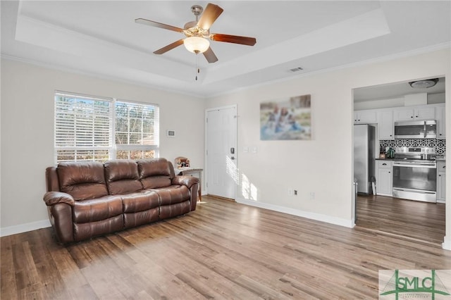 living area featuring a tray ceiling and wood finished floors