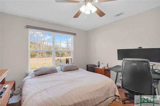 bedroom with wood finished floors, visible vents, and ceiling fan