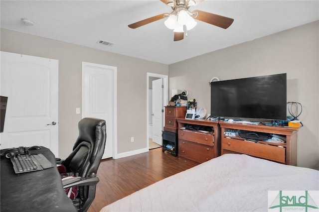 bedroom featuring a ceiling fan, wood finished floors, visible vents, and baseboards