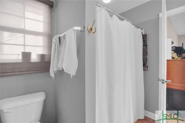 bathroom featuring a shower with shower curtain, toilet, and tile patterned floors