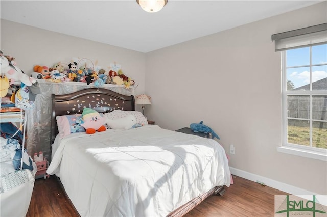 bedroom featuring baseboards, multiple windows, and wood finished floors